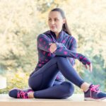 Negli ultimi anni l’abbigliamento sportivo femminile ha subito una trasformazione significativa, passando da semplice dotazione funzionale a segmento strutturato della moda tecnica e del lifestyle. La crescita della pratica sportiva tra le donne, sia a livello amatoriale sia in contesti più organizzati come fitness, running e discipline in palestra, ha portato a una maggiore attenzione verso capi capaci di unire prestazione, comfort ed estetica. Tra i prodotti più diffusi si trovano i leggings tecnici, ormai diventati un elemento centrale dell’abbigliamento sportivo. Realizzati in tessuti elasticizzati e traspiranti, sono progettati per garantire libertà di movimento e supporto muscolare. Le versioni a vita alta sono particolarmente apprezzate per la stabilità durante esercizi dinamici come squat, affondi e attività cardio. Accanto ai leggings si sono affermati anche i pantaloncini compressivi, utilizzati soprattutto nelle stagioni calde o nelle attività outdoor. Un altro elemento chiave è rappresentato dai reggiseni sportivi, studiati per offrire sostegno durante l’attività fisica. La scelta del modello varia in base all’intensità dello sport praticato: dalle attività a basso impatto come yoga e pilates fino a discipline ad alta intensità come corsa e HIIT. Le differenze riguardano principalmente il livello di compressione, la struttura delle spalline e la capacità del tessuto di assorbire il sudore. Le magliette tecniche completano spesso il look sportivo femminile. I materiali più utilizzati sono fibre sintetiche leggere, progettate per favorire la traspirazione e ridurre l’accumulo di umidità. Negli ultimi anni si è diffusa anche l’adozione di tessuti sostenibili, realizzati con materiali riciclati, in linea con una crescente attenzione ambientale nel settore dell’abbigliamento sportivo. Un ruolo importante è rivestito anche dalle felpe e dai capi da riscaldamento, utilizzati prima e dopo l’allenamento. Le versioni con zip, cappuccio e tessuti termici leggeri sono particolarmente diffuse nelle discipline outdoor e nelle attività invernali. La stratificazione degli indumenti consente di adattare l’abbigliamento alle condizioni climatiche e all’intensità dell’attività. Le calzature rappresentano un ulteriore elemento centrale. Le scarpe da training femminili sono progettate per garantire stabilità, ammortizzazione e reattività nei movimenti multidirezionali. Nei modelli da running, invece, l’attenzione si concentra sull’assorbimento dell’impatto e sulla leggerezza della struttura. La scelta della scarpa dipende quindi in modo diretto dal tipo di attività praticata. Accanto agli aspetti tecnici, l’abbigliamento sportivo femminile ha assunto anche una forte dimensione estetica. Colori, fantasie e design sono diventati elementi sempre più rilevanti, con collezioni che seguono le tendenze stagionali della moda. L’integrazione tra funzionalità e stile ha contribuito a rendere molti capi utilizzabili anche al di fuori del contesto sportivo, in un fenomeno che viene spesso definito athleisure e vale oltre 400 miliardi a livello globale, interessando soprattutto (ma non solo) la Gen Z. Nel contesto professionistico, la scelta dell’abbigliamento assume ulteriori implicazioni legate alla performance e alla personalizzazione. L'abbigliamento fa sempre la sua parte, anche quando si gareggia a livello agonistico. Forse gli spettatori non se ne rendono sempre conto perché per chi osserva da fuori l'occhio cade perlopiù sulle statistiche o sulle scommesse sportive, ma molte atlete hanno delle specifiche preferenze su come vestirsi prima di una prestazione importante, perché l'aderenza e la comodità sono fondamentali se per ottenere un risultato migliore rispetto a un'avversaria bastano pochi decimi di secondo su una pista d'atletica o in una vasca. Un altro trend in crescita riguarda la personalizzazione dei capi, con sempre più marchi che offrono la possibilità di adattare colori, tagli e dettagli in base alle preferenze individuali. Questo fenomeno è particolarmente evidente nel fitness e nelle attività di gruppo, dove l’aspetto estetico si integra con la funzione tecnica.